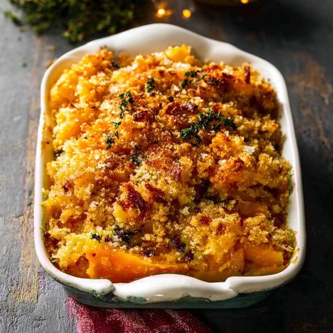 A cheesy butternut squash casserole in a white bowl.