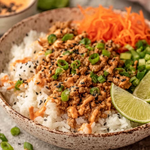 A bowl of rice with ground turkey and bang bang sauce.