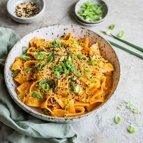 A bowl of pasta with a spoon in it.