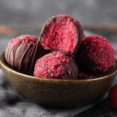 A bowl of chocolate covered raspberry truffles.