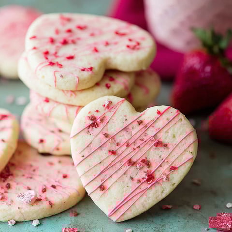A stack of heart shaped cookies with red frosting.