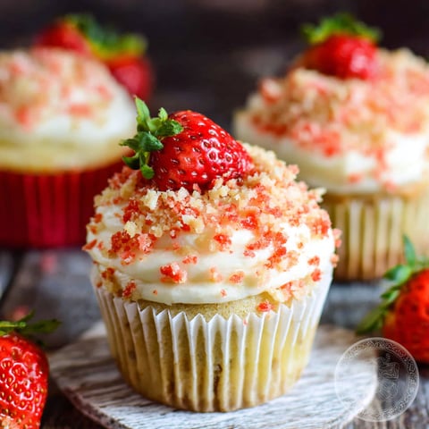 A close up of a cupcake with strawberries on top.